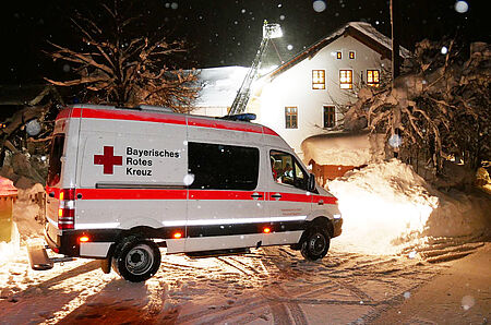 Krankenwagen des Münchner Roten Kreuzes vor Haus im Landkreis Miesbach