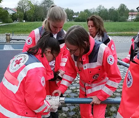 Rotkreuzhelfer*innen in Uniform setzen eine Schlauchverbindung zusammen